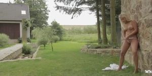 Blonde girl teasing grass in forest in the garde