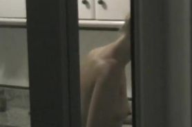 Window shot of a naked woman in the kitchen