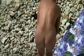 Nudist woman in rocky beach smoking