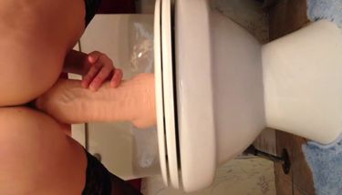 Toying with huge dildo on toilet sink
